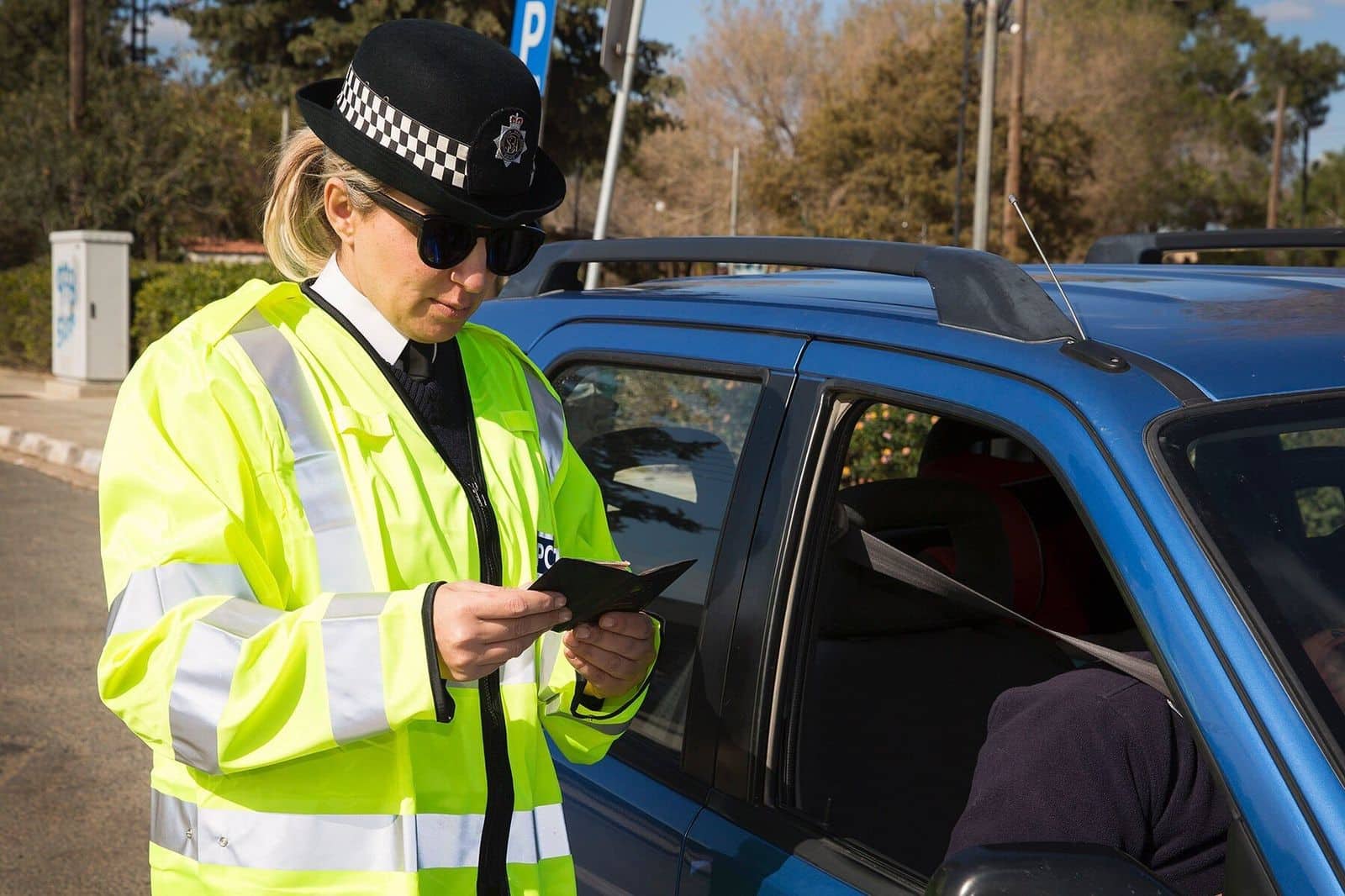 A female police officer talking to a driver through his car window after stopping him for a traffic violation and issuing penalty points
