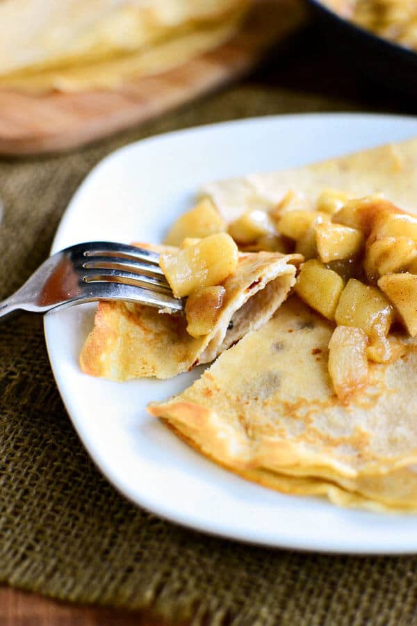 Apple pie crepes are made with a whole wheat crepes recipe, then stuffed with vanilla yogurt crepe filling and topped with apple pie filling. They're one of the best apple recipes to make for a fall weekend brunch! plate of whole wheat apple cider crepes stuffed with vanilla yogurt and topped with apple pie filling
