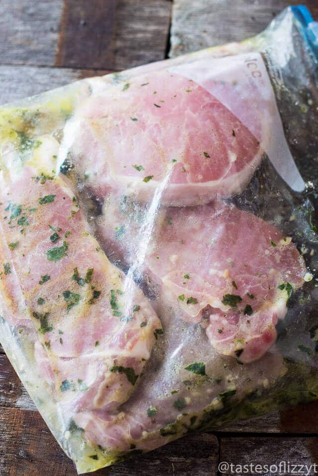 Basil Lemon Pork Chops Marinade is an easy, 4-ingredient marinade recipe that makes the most tender Grilled Basil Lemon Pork Chops. Throw ingredients together in under 5 minutes, marinate, and grill! A Paleo, Whole30, gluten free recipe for the family. #glutenfree #whole30 #paleo #porkrecipes #porkchops boneless pork chops in a zip top plastic bag with a 4 ingredient lemon basil marinade