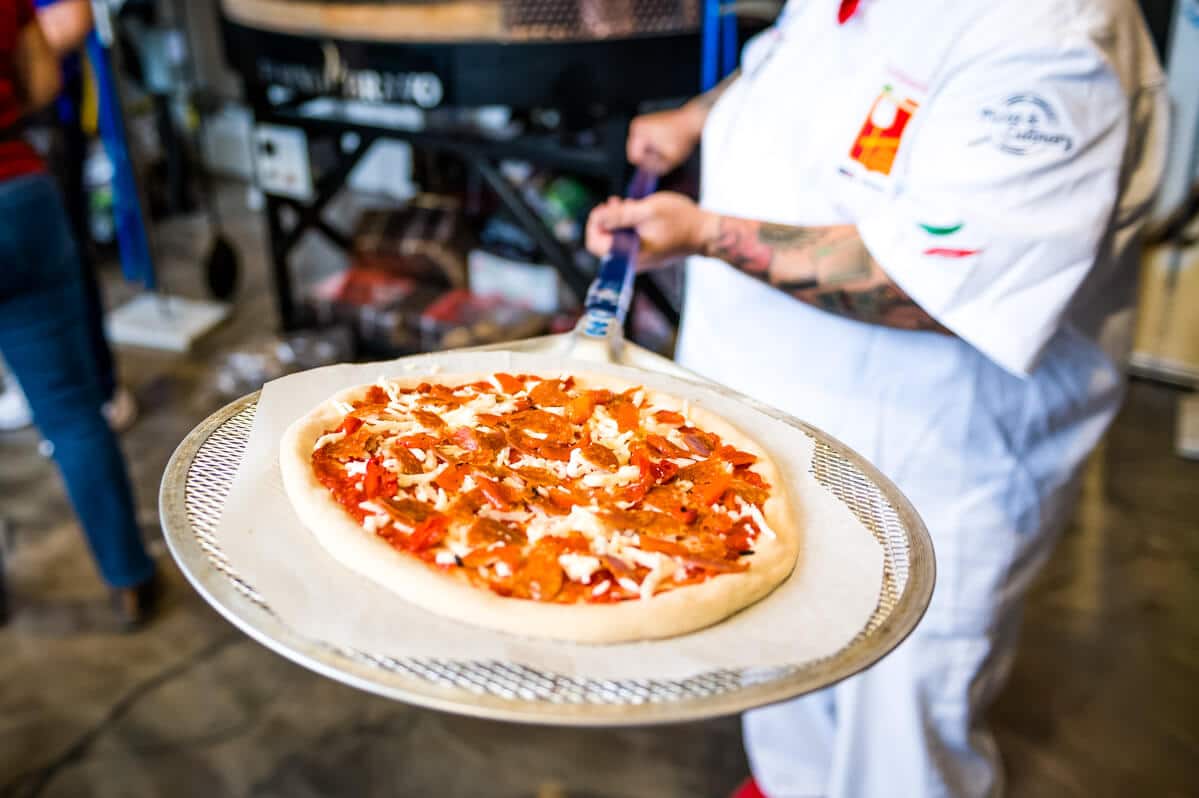unbaked pizza on a pizza screen