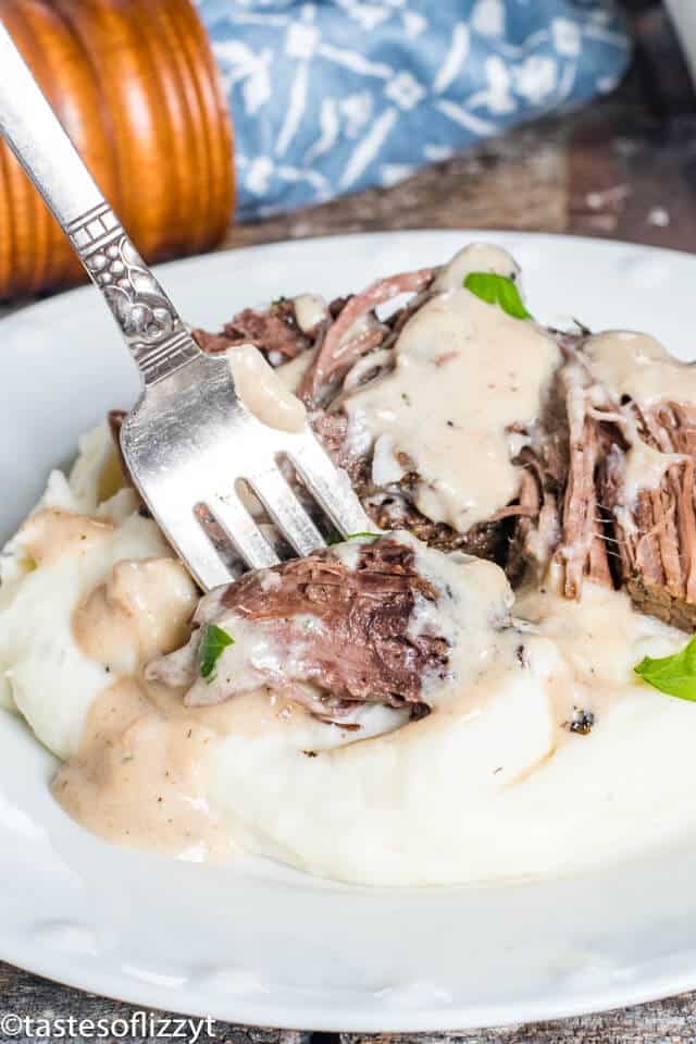 A plate of food with a fork, with Beef and Pot roast