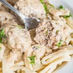 homemade Swedish meatballs on a bed of egg noodles. One meatball has been cut in half with a fork