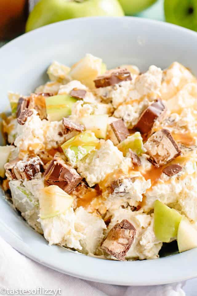Snickers Apple Salad is an easy picnic side dish or dessert that everyone will love! Surprise your guests with this sweet dessert salad filled with candy bars, caramel and apples. It's one of the best apple recipes you can make for a party! bowl filled with Snickers apple salad