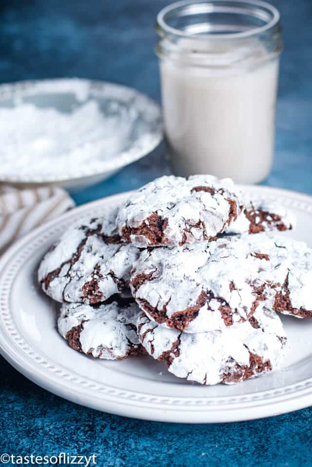Chocolate crinkle cookies are chewy, fudgy chocolate Christmas cookies with a topping of crackled powdered sugar. This classic Christmas cookie recipe is a must for any holiday cookie platter. #christmascookies #chocolatecrinklecookies #recipes plate of chocolate Christmas cookies