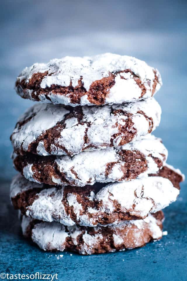 Chocolate crinkle cookies are chewy, fudgy chocolate Christmas cookies with a topping of crackled powdered sugar. This classic Christmas cookie recipe is a must for any holiday cookie platter. #christmascookies #chocolatecrinklecookies #recipes stack of chocolate crinkle cookies