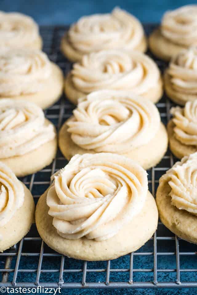 Frosted Eggnog Cookies are made with a soft sugar cookie recipe that's spiked with eggnog. The soft eggnog cookies have a swirl of eggnog frosting on top. #christmascookies #eggnog #recipes frosted eggnog cookies on a wire cooling rack