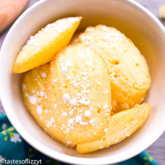 Lemon madeleine cookies are delicious cake-like cookies with a crispy exterior and soft interior. This madeleines recipe pairs perfectly with coffee or tea. #madeleines #cookierecipes white bowl filled with lemon madeleine cookies