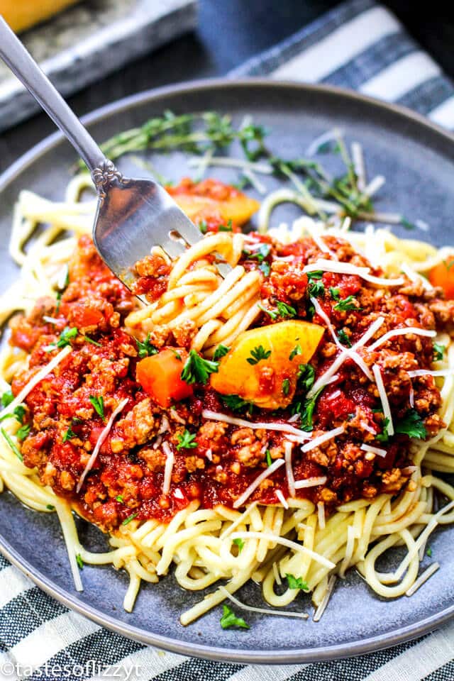 A bowl of food on a plate, with Sauce and Pasta