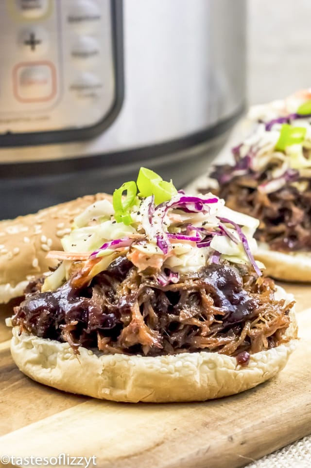 A close up of a sandwich sitting on top of a wooden cutting board, with Pulled pork