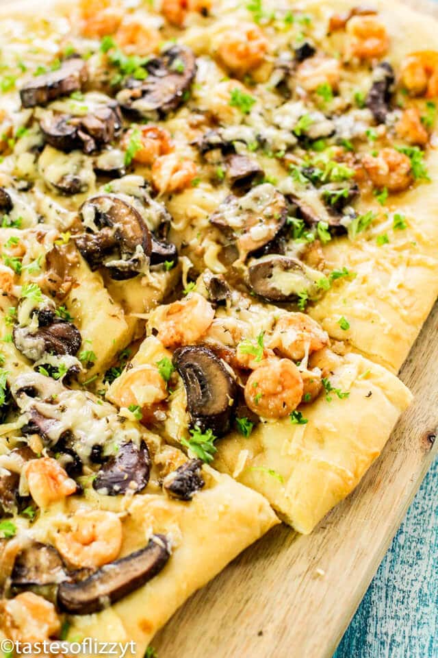 A pizza sitting on top of a wooden cutting board, with Flatbread