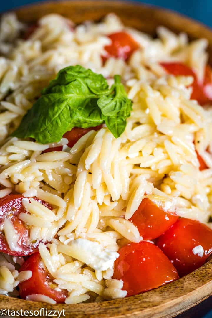 A close up of a bowl of orzo with feta and tomatoes