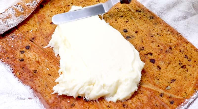 spreading pumpkin roll filling on a cake