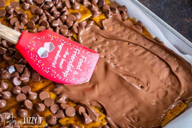 spreading chocolate chips on top of saltine toffee