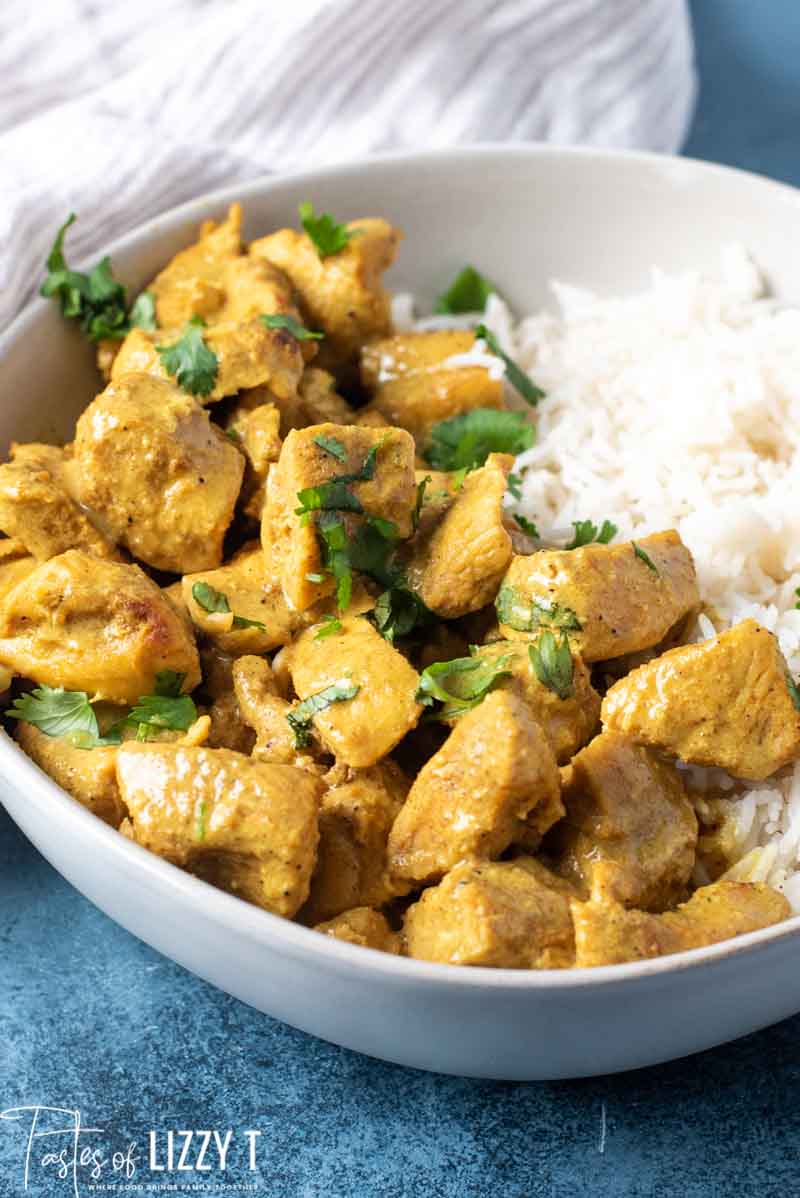 A bowl of food on a plate, with Curry and Chicken