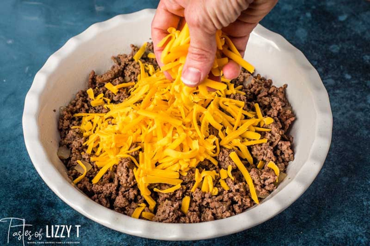 sprinkling cheese over beef for a casserole