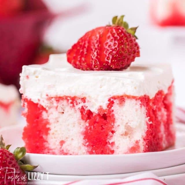 piece of strawberry jello poke cake with a strawberry on top