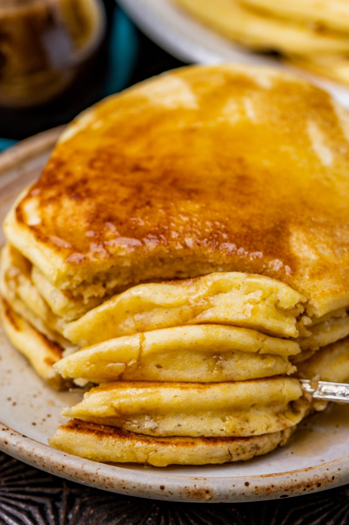 closeup of a fork cut into a stack of 4 pancakes