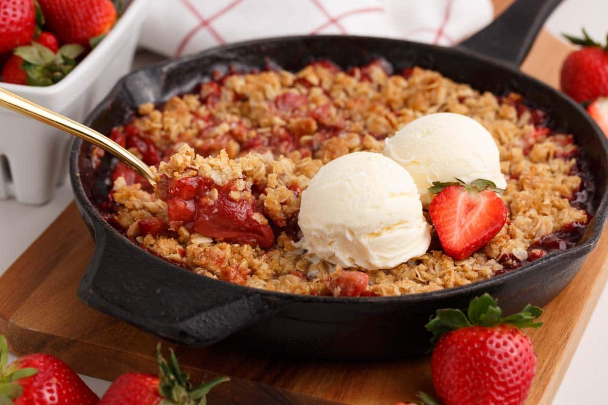 strawberry crisp in a cast iron skillet with ice cream