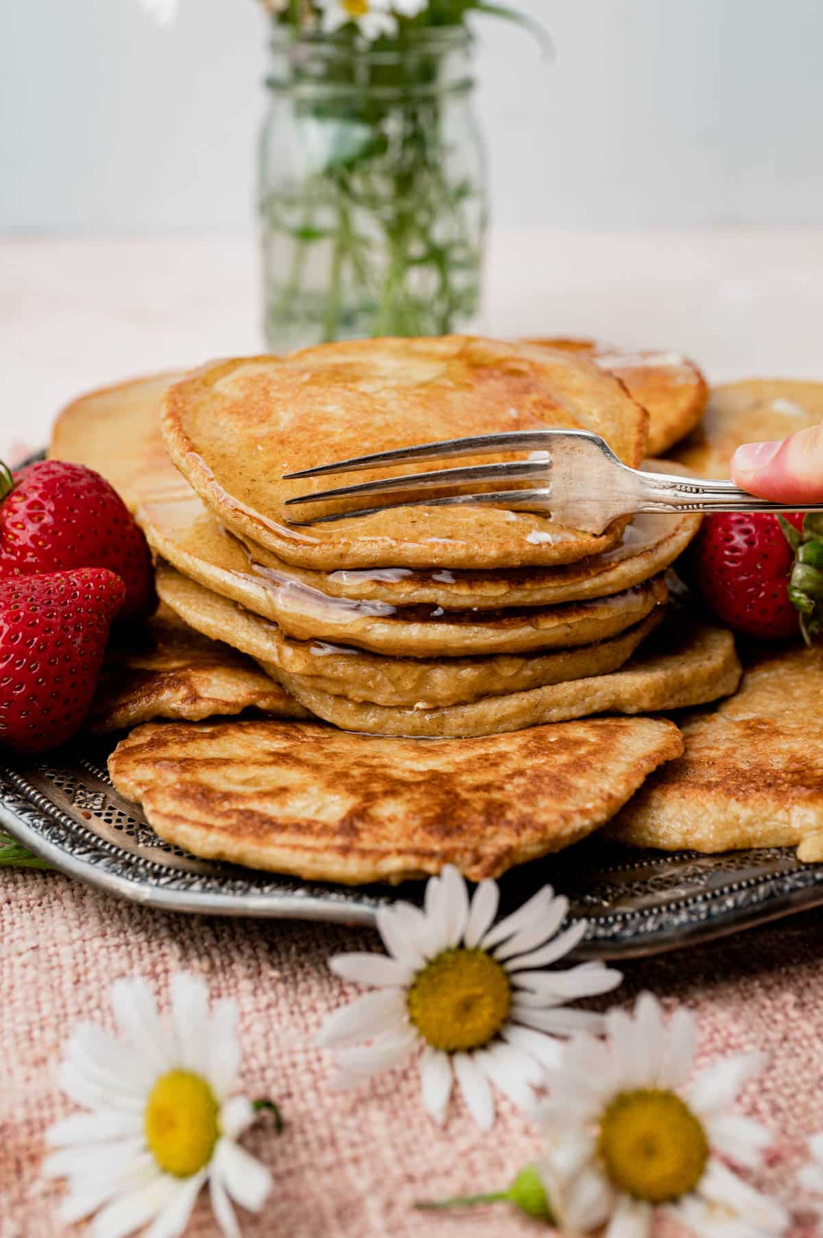 a fork cutting into a stack of pancakes
