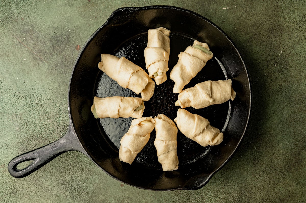 unbaked crescent roll apple dumplings in a pan