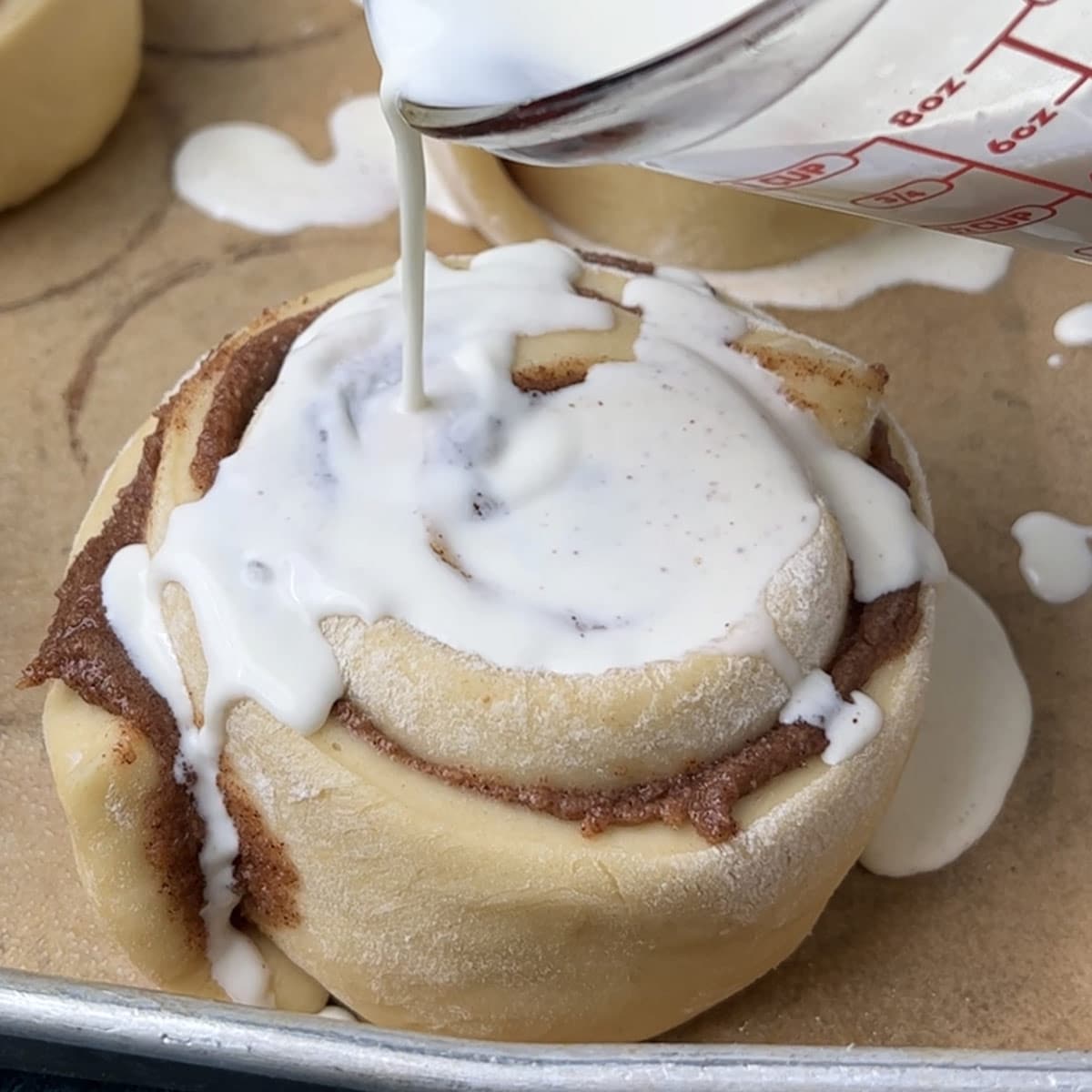 heavy cream pouring over cinnamon rolls