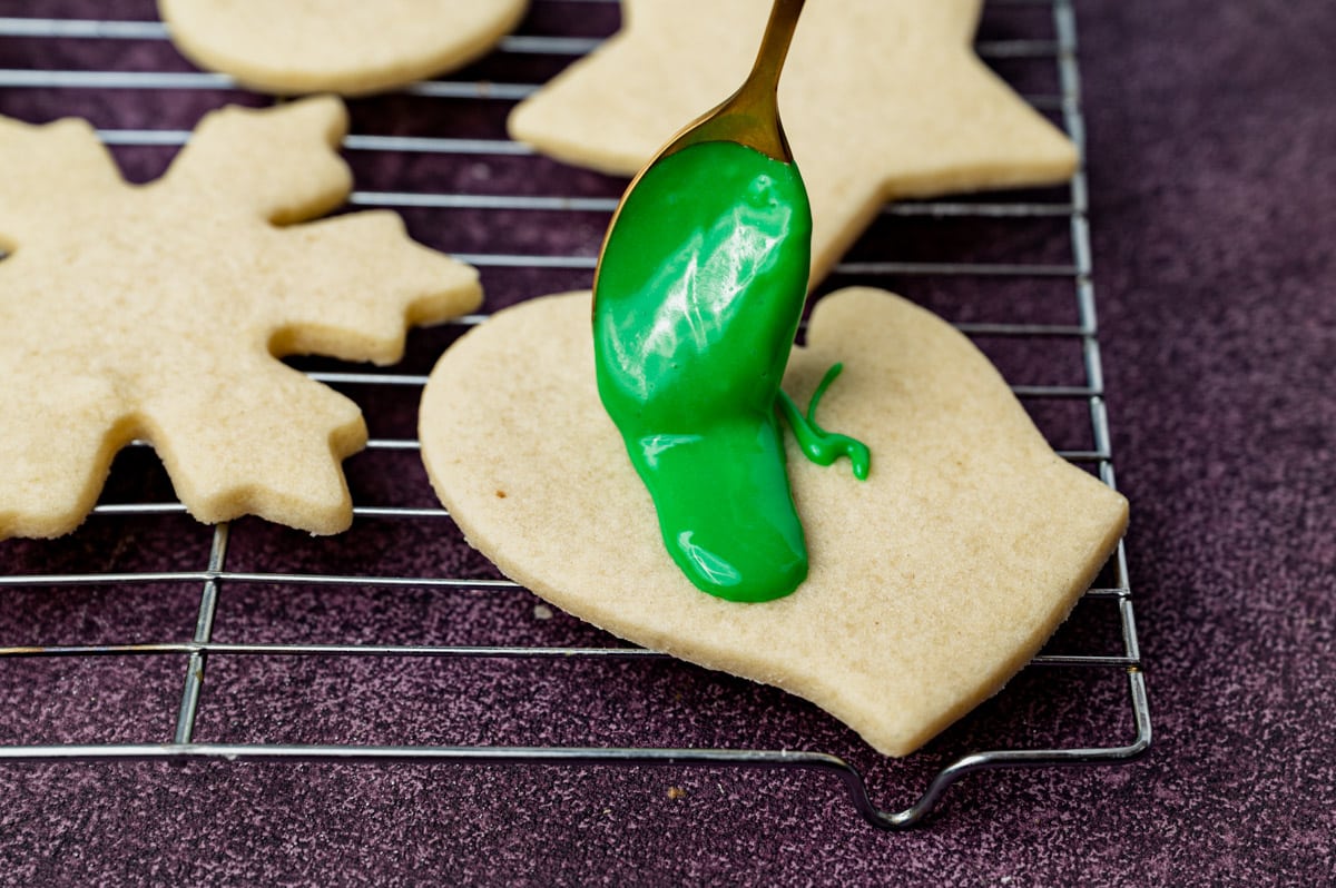 spooning sugar cookie icing on a cut out cookie