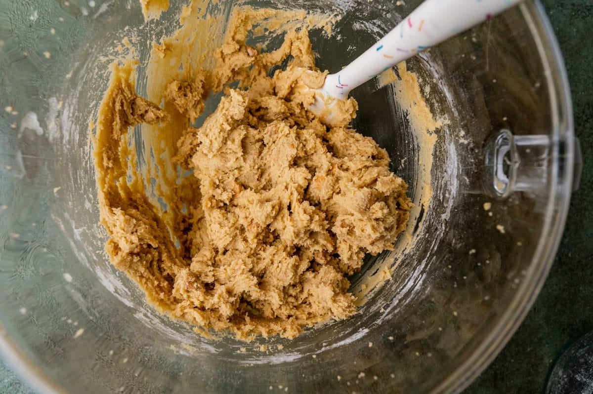 cookie dough in a mixing bowl with a rubber spatula