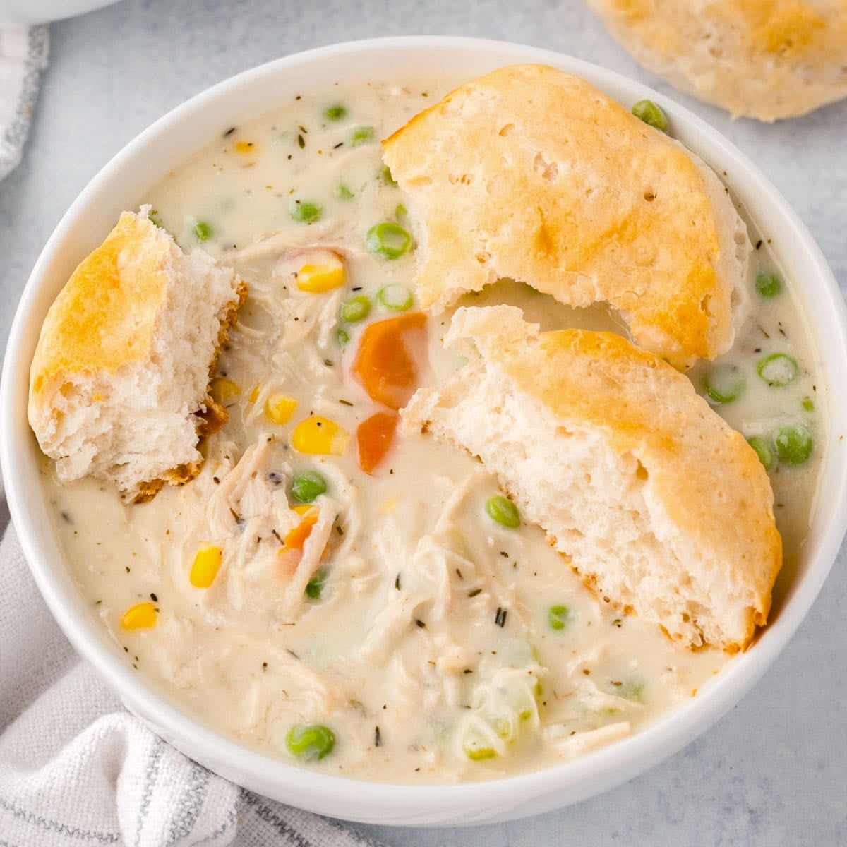 a bowl of chicken pot pie soup with a biscuit on top
