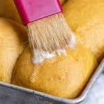butter spreading on the top of a warm pumpkin roll