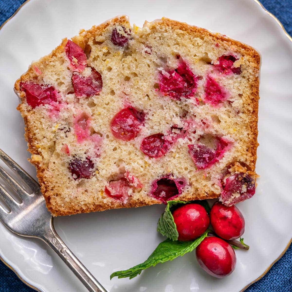 a slice of cranberry orange bread on a plate with a fork