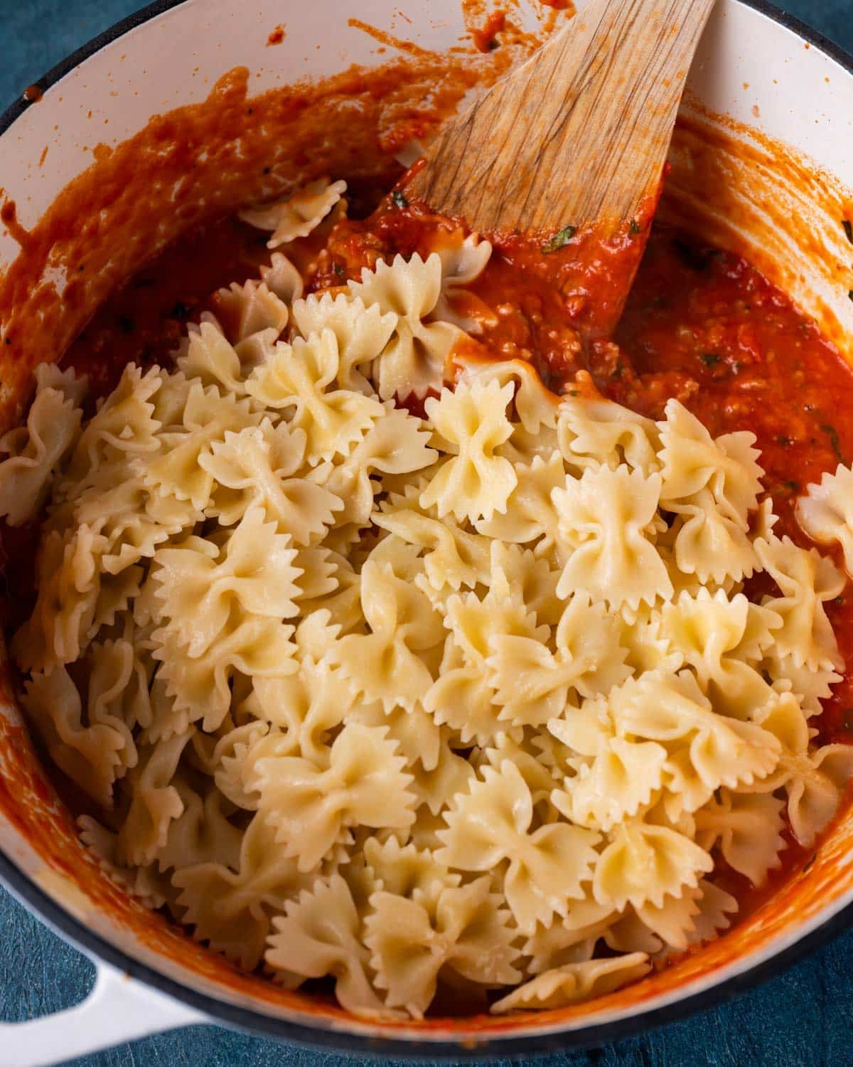 bowtie pasta on top of spaghetti sauce in a pan