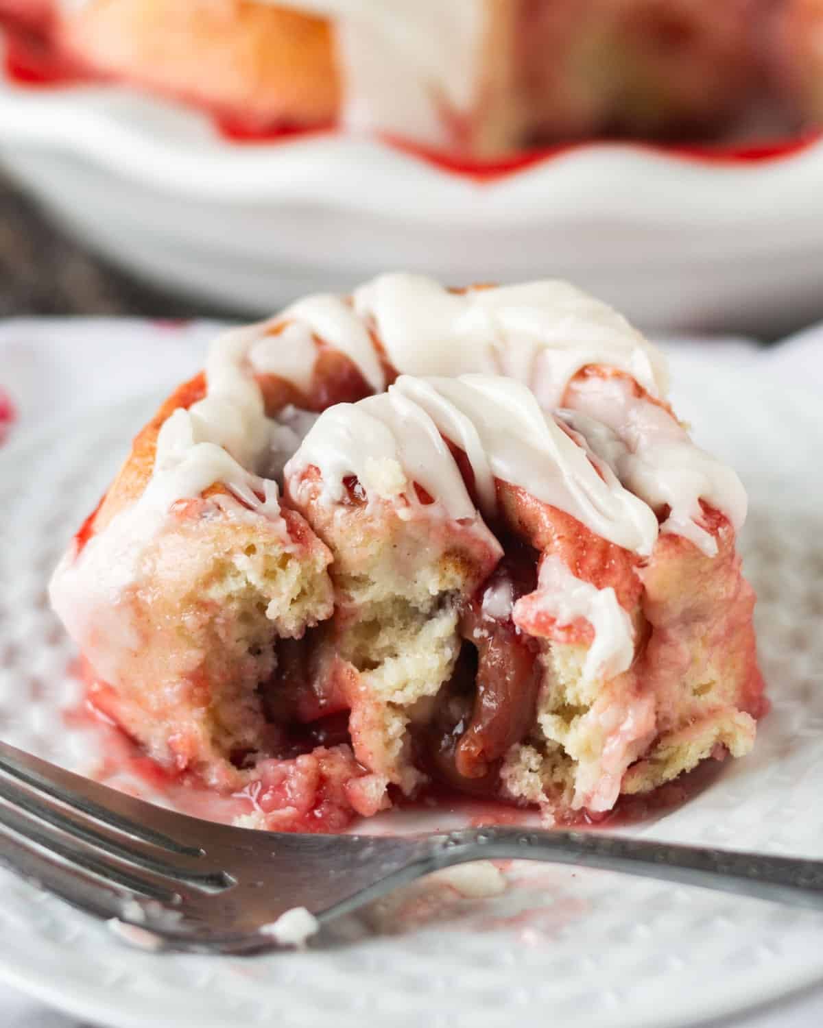 a cherry roll sitting on a plate with a bite out