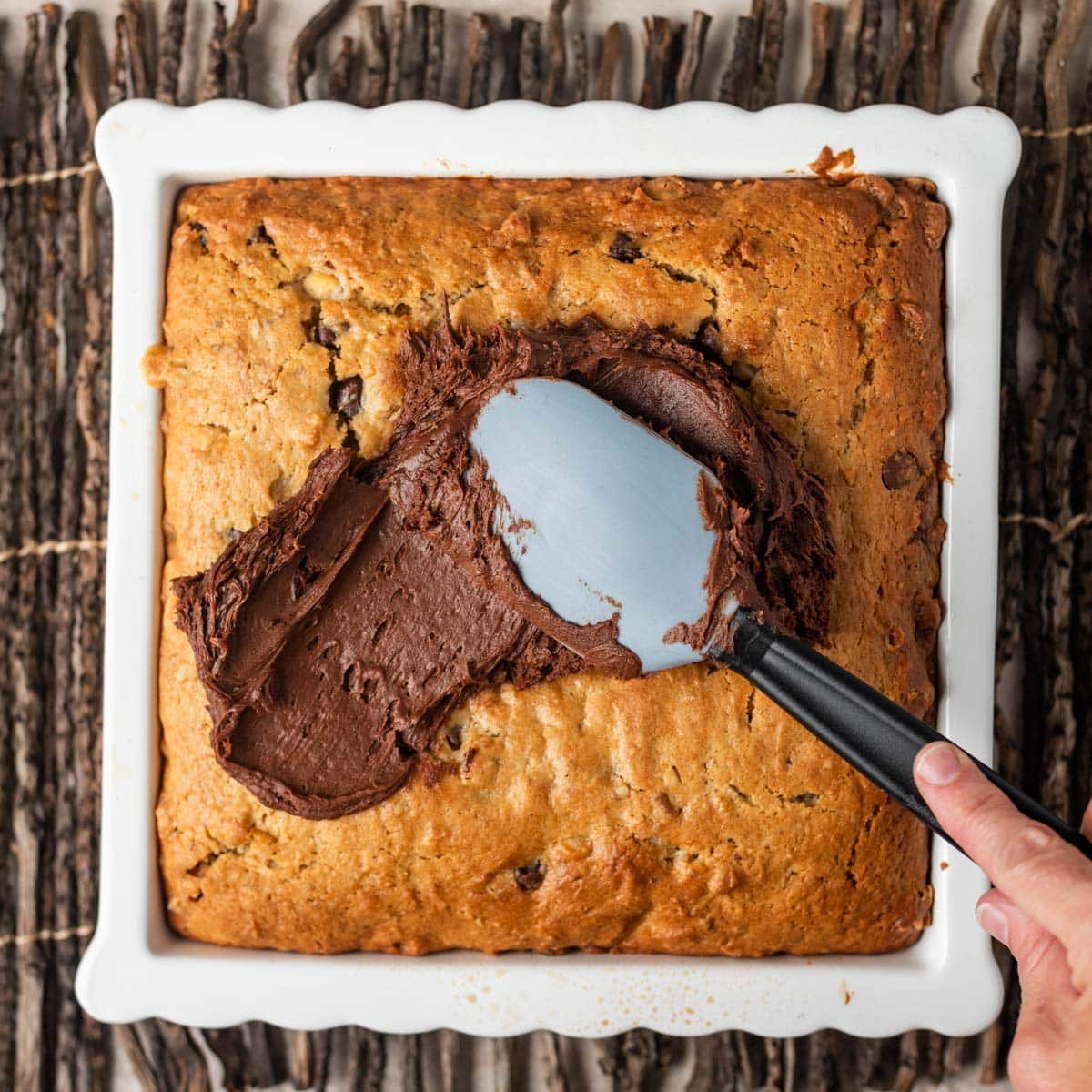 spreading chocolate frosting on a chocolate snack cake