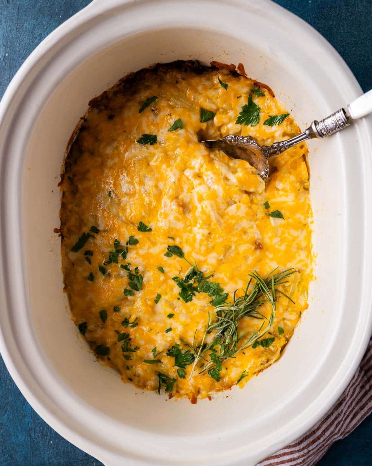 overhead view of crockpot hashbrown casserole with a spoon in it