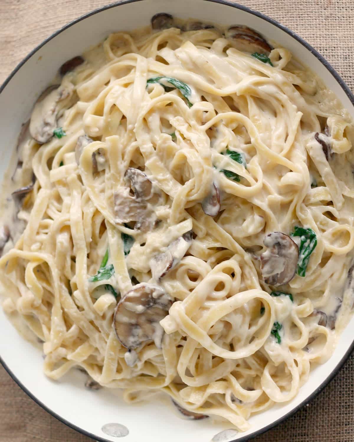 a skillet of pasta with mushroom alfredo sauce