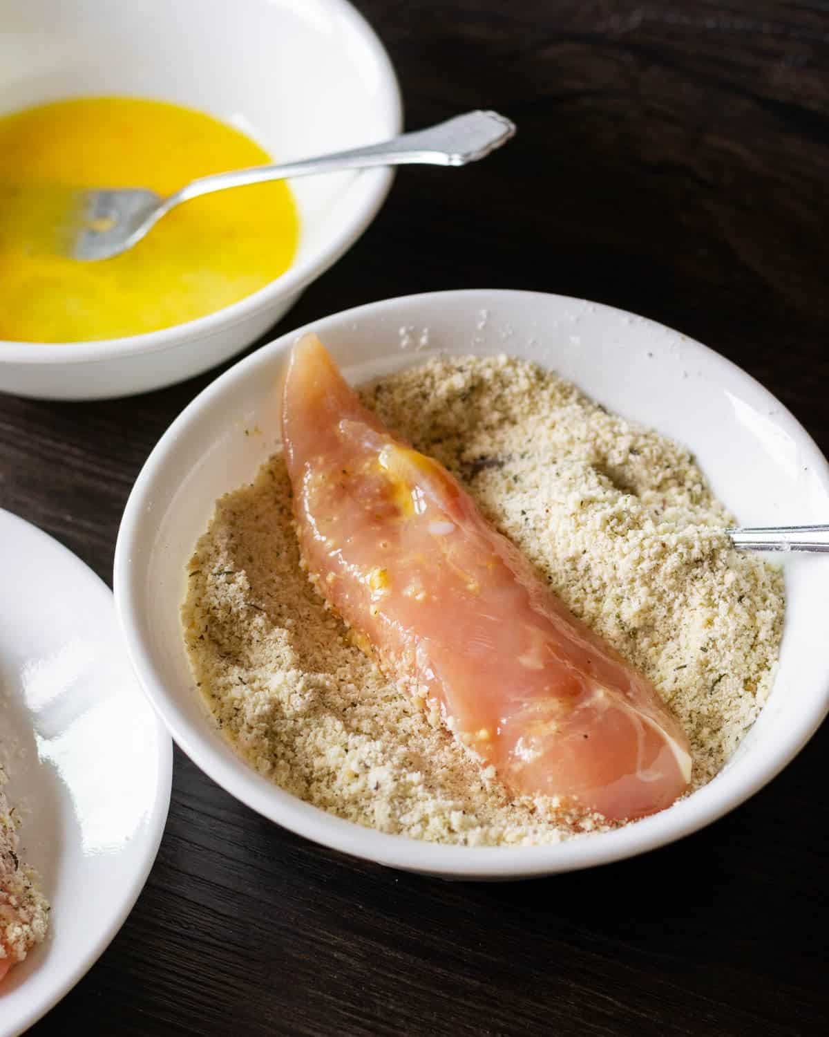 a chicken tender sitting in a bowl of breading