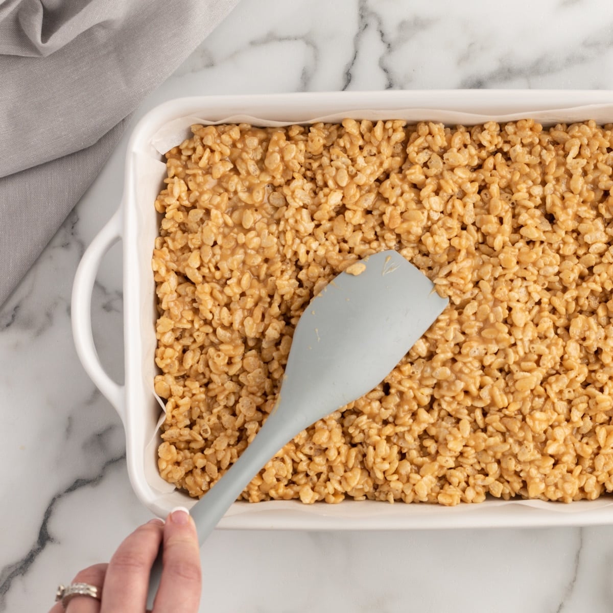 pressing rice krispies in a pan for scotcheroos