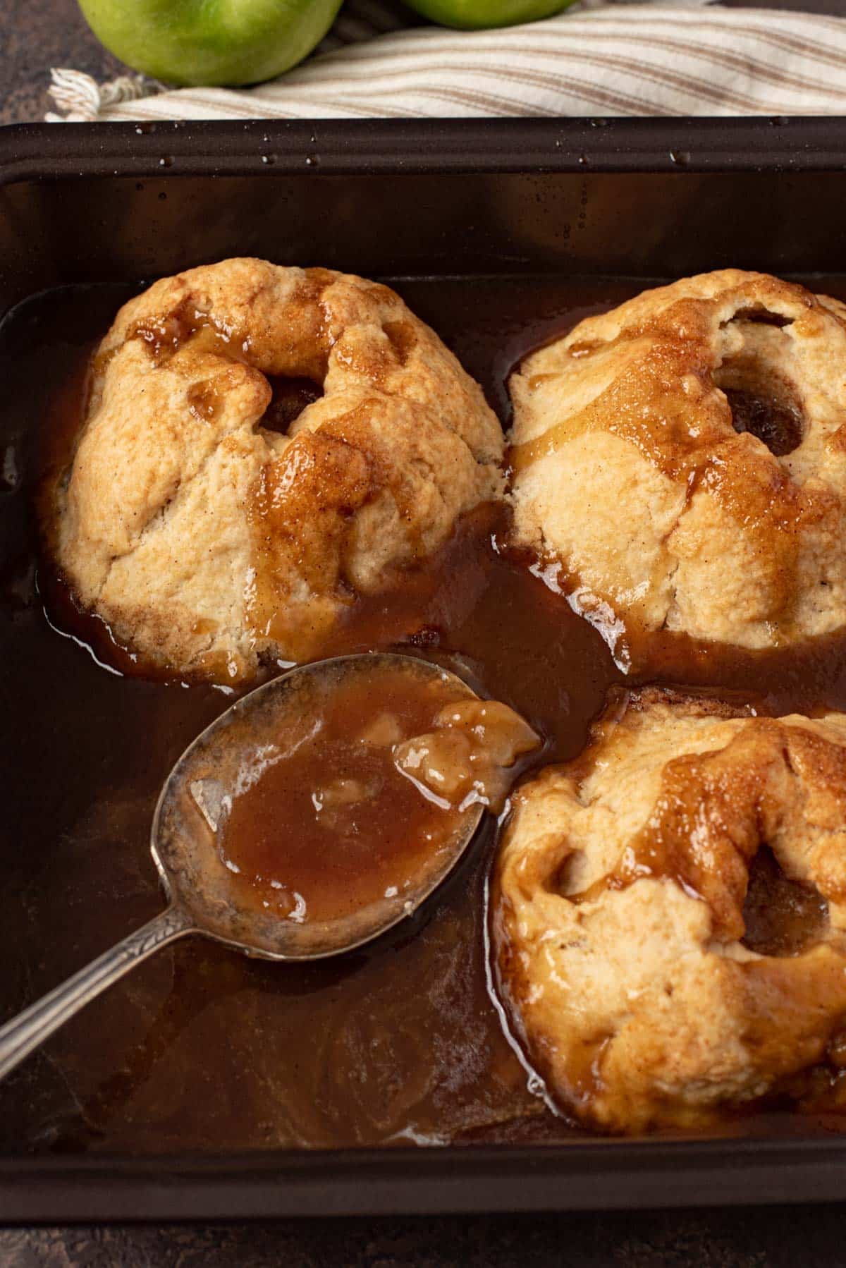 3 apple dumplings in a pan with a spoon