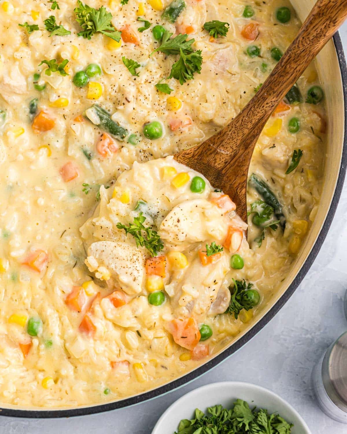 Creamy chicken and rice with veggies in a skillet with a spoon