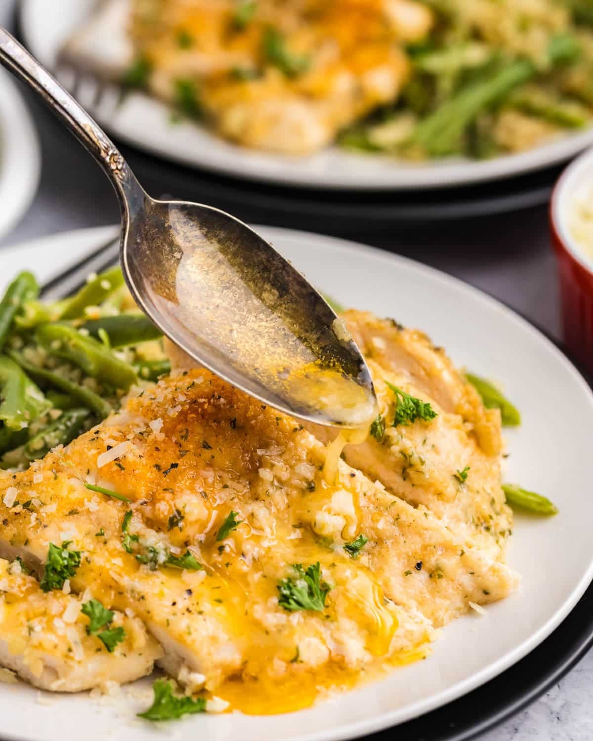 a spoon pouring garlic butter over chicken