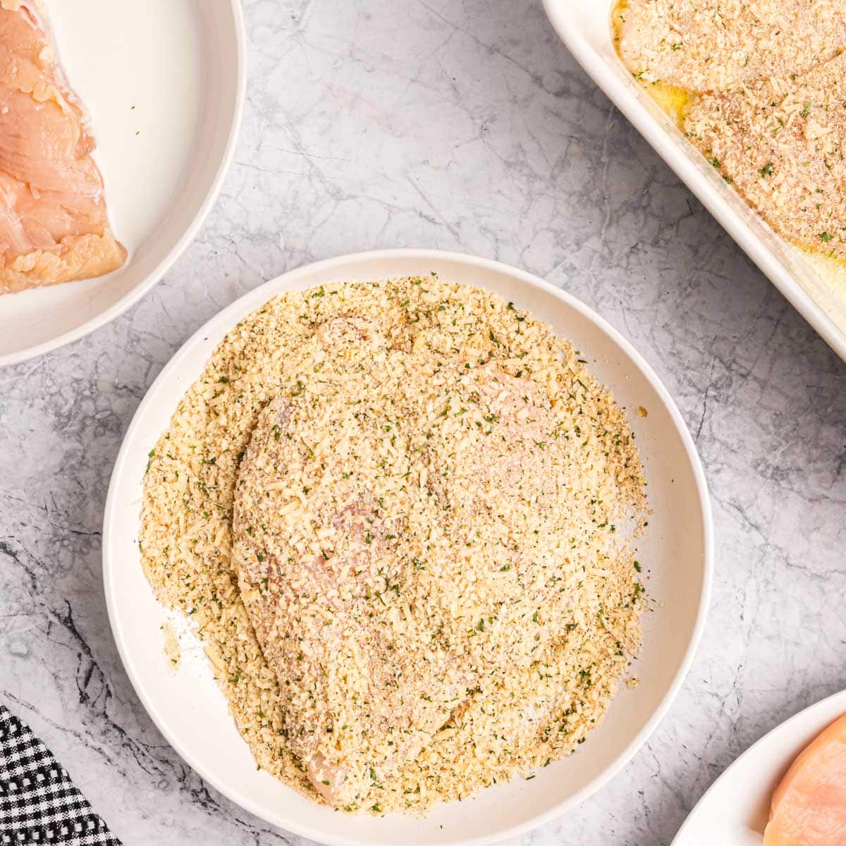 a piece of chicken with bread crumbs over it, ready to bake
