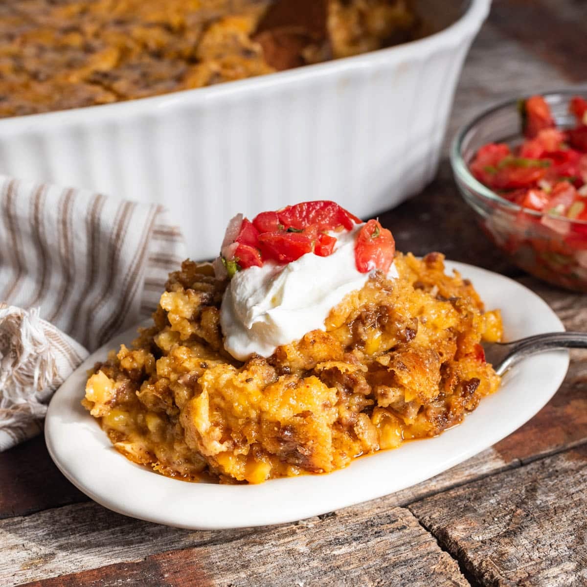 taco corn casserole on a plate with sour cream and fresh salsa