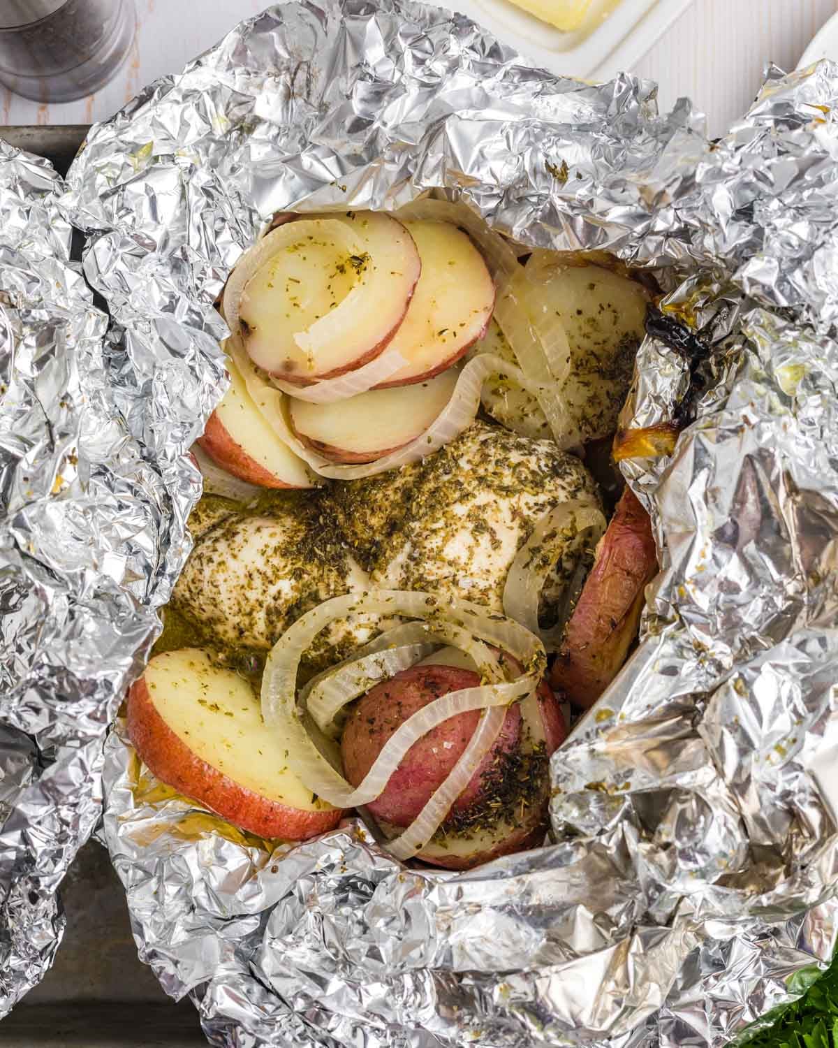 an opened chicken and potato foil packet