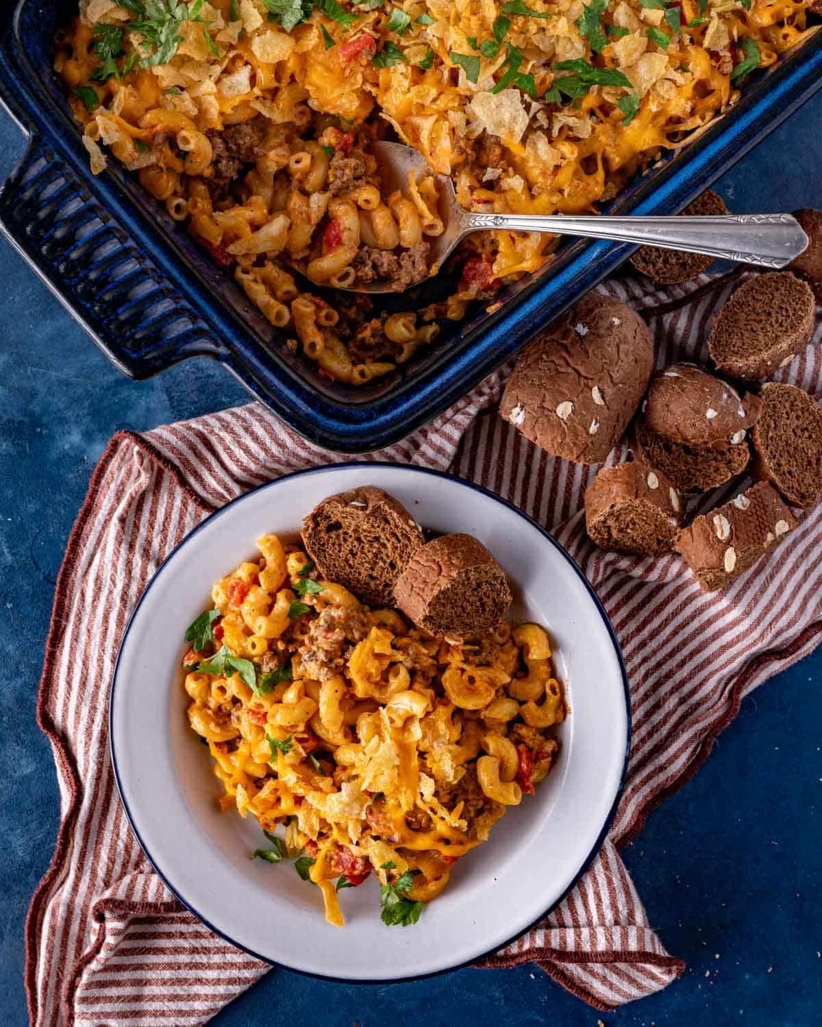 hamburger macaroni casserole on a table with sliced bread