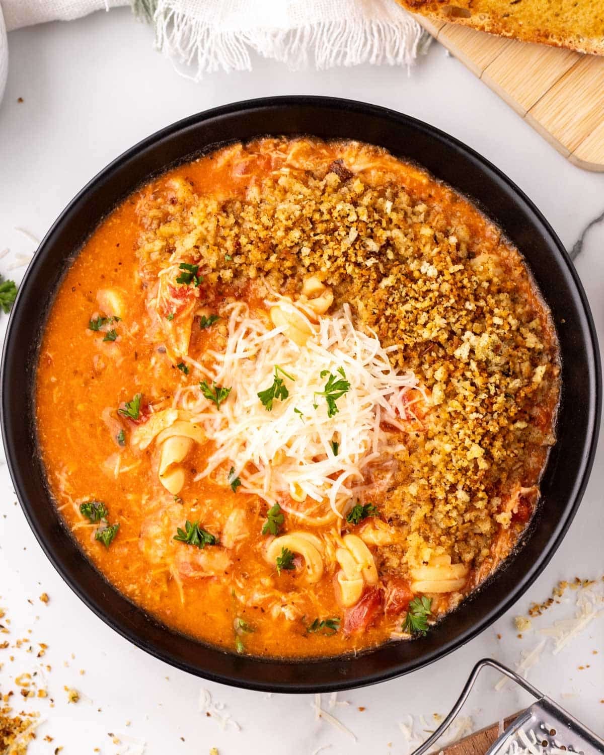 a bowl of chicken parmesan soup with bread crumbs and cheese