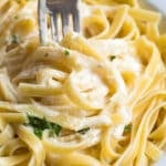 a fork in bed of alfredo sauce with fettucchini