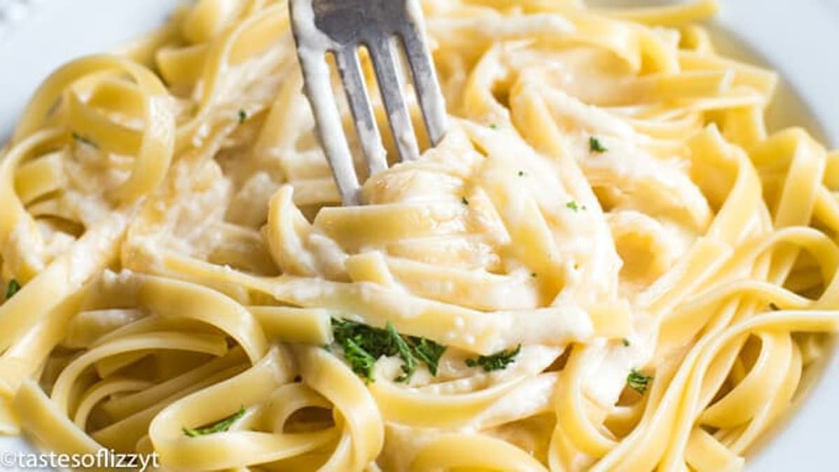 a fork in bed of alfredo sauce with fettucchini
