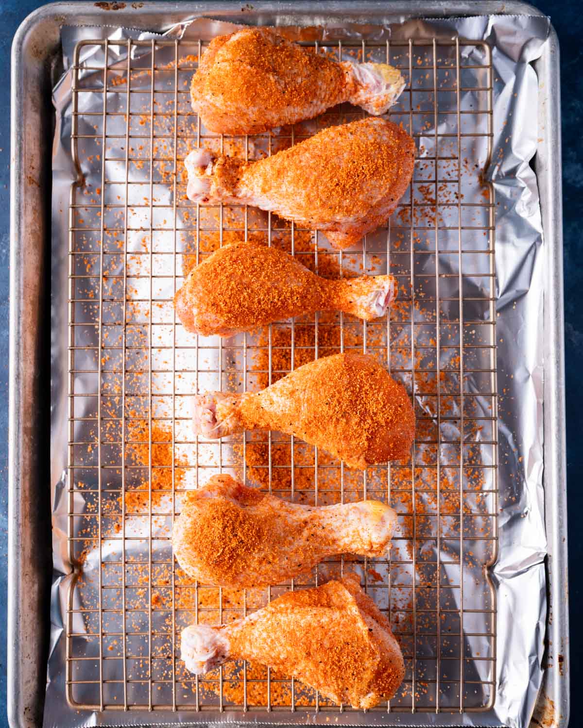 seasoned chicken drumsticks on a wire baking rack