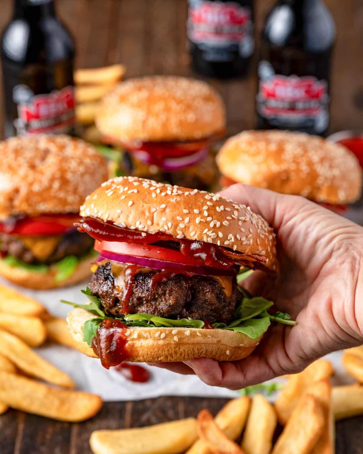 a hand holding a bbq bacon burger