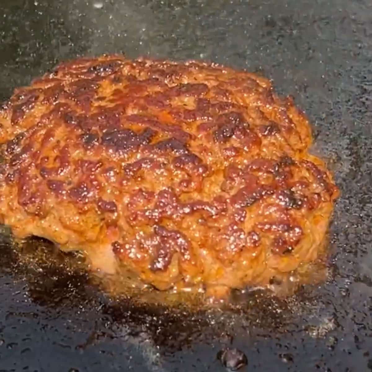 a burger frying on a grill